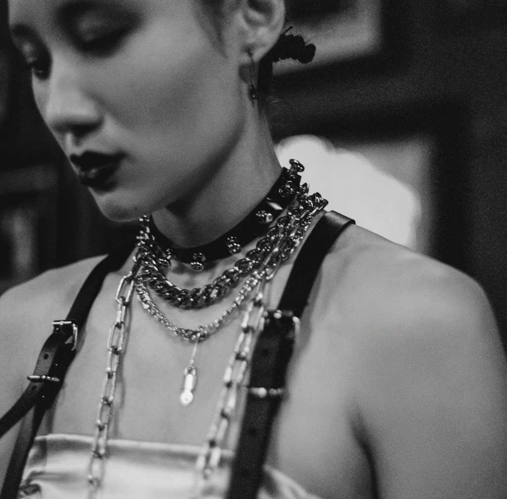 Stylish monochrome portrait featuring a woman wearing a choker and layered chains.